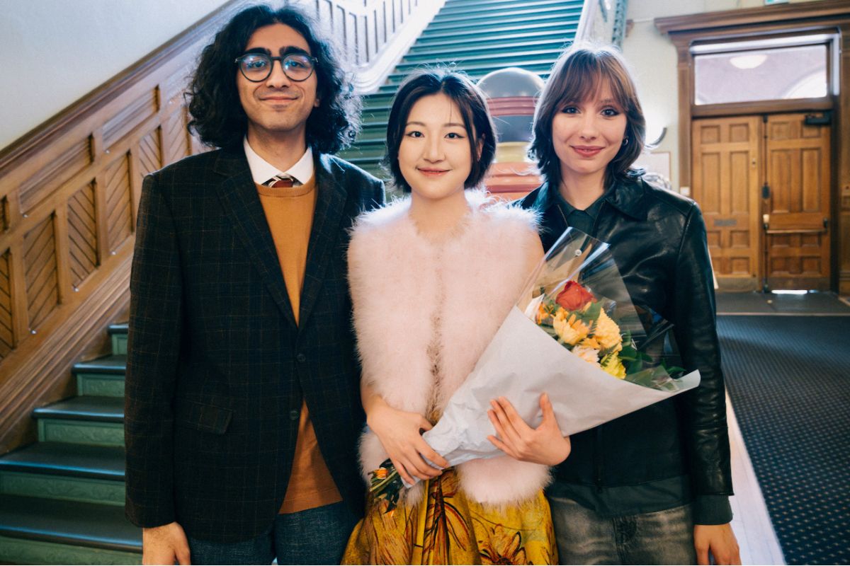 Zhehui Xie holds a bouquet of flowers, with friends standing to her left and right.