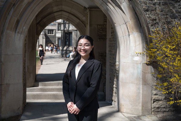Fabiola Astrid Cruz Li, a Victoria College student graduating this June, is standing near an archway on Victoria College campus.
