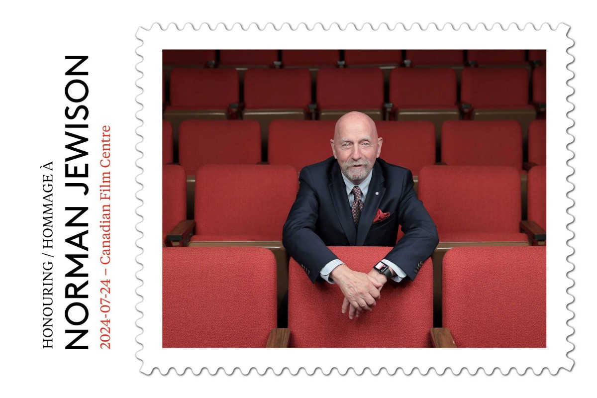 Peter Bregg seated in an auditorium with red seats, looking ahead attentively.